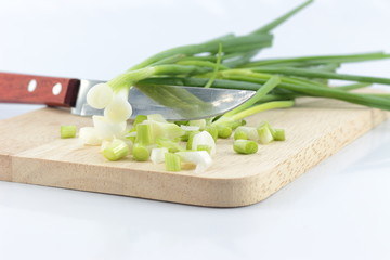 chopped green onions on striped wooden board