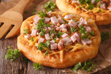langos deep fried with cheese and ham close-up. Horizontal
