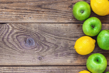 Background with fresh lemons and green apples on grunge wooden b