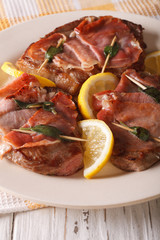 Italian beef Saltimbocca with sage, ham and lemon close-up. Vertical
