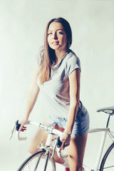 Fototapeta na wymiar Young woman on white retro bicycle in studio