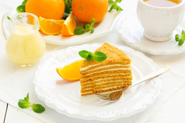 Homemade honey cake with orange cream on a white plate.