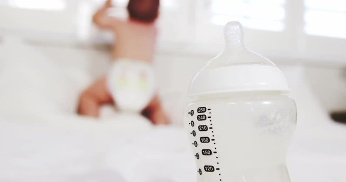 Close up on baby's bottle with the baby on background