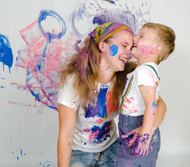 Mother and son paint the walls. Child himself dirty in the paint and looks into the camera. Child...