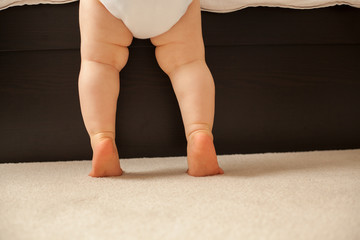 Baby auf zehenspitzen am Bett