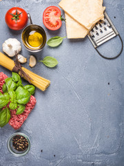Ingredients for cooking pasta Bolognese on grey concrete background, top view