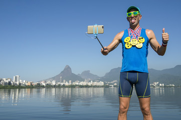 Athlete taking selfie wearing gold medals with bright yellow emoji faces with smartphone on selfie stick in Rio de Janeiro, Brazil