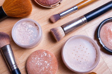 Face makeup cosmetics on a light wooden floor.