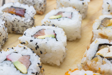 Different Sushi rolls,wasabi and ginger on a plate on wooden bac
