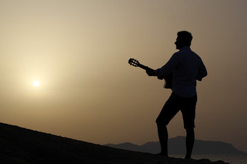 dark silhouette of a man musician playing guitar