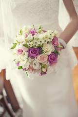 Wiązanka ślubna z kolorowych kwiatów panny młodej na tle sukni ślubnej
