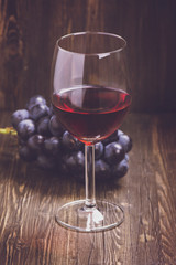Glass of red wine and grapes. Toned vintage image