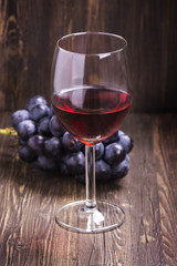 Glass of red wine and grapes. Toned vintage image