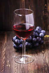 Glass of red wine and grapes. Toned vintage image