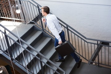 Businessman holding briefcase and climbing staircase