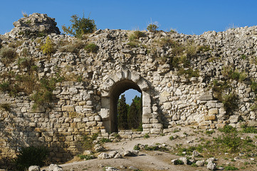 Ruins of ancient Greek sandstone wall with an arch doorway