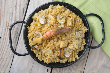 Vegetable paella with seafood on a wooden background