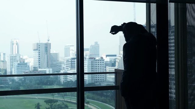 Sad, desperate businessman standing by window in the office
