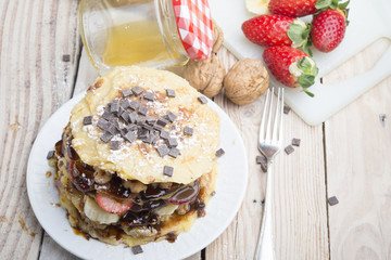 Pancakes with berries, fruits, chocolate, pine nuts and honey on