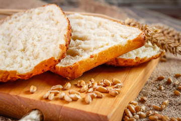 Fresh slices whole bread and wheat on the wooden board on burlap