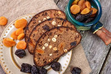 Sliced rye bread with prunes, dried apricots and hazelnut on old rustic table. Top view.