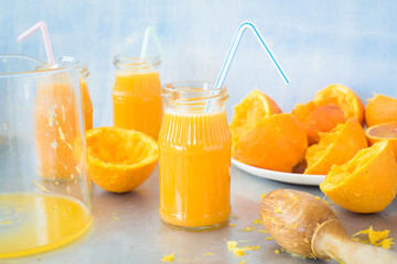 Fototapeta na wymiar Freshly squeezed orange juice in jar with drinking straw on metallic countertop. Selective focus.