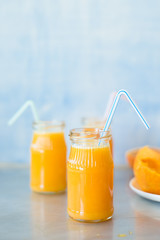 Freshly squeezed orange juice in jar with drinking straw. Selective focus.