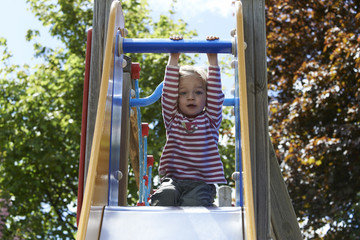 Obraz premium Happy two-year child girl on slide playground area