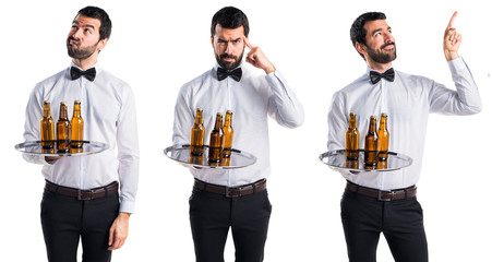 Waiter with beer bottles on the tray thinking