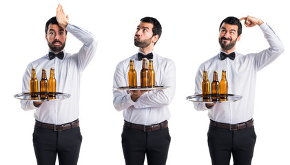 Waiter with beer bottles on the tray having doubts