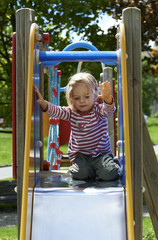 Fototapeta na wymiar Happy two-year child girl on slide playground area