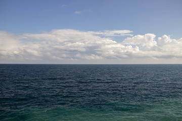 The dark sea water and sky with clouds, visible horizon