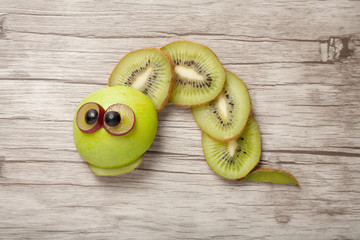 Caterpillar made of kiwi, apple and grape on desk