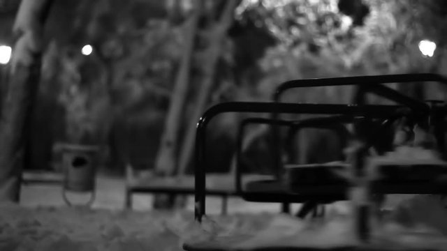 Night Winter Sad empty merry go round spinning in a playground black and white footage