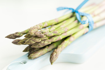 Bunch of fresh asparagus on a blue wooden cutting board
