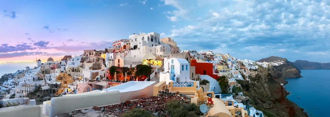 Foto op Canvas Picturesque panorama, Old Town of Oia or Ia on the island Santorini, white houses, windmills and church with blue domes at sunset, Greece © Kavalenkava