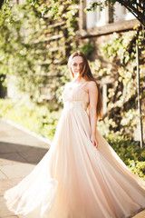 Fototapeta premium Attractive young woman with long dress enjoying her time outside in park sunset background