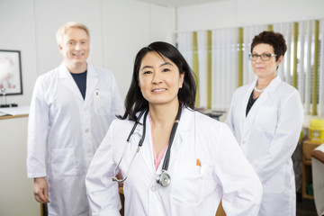 Fototapeta premium Confident Female Doctor Smiling While Standing With Colleagues