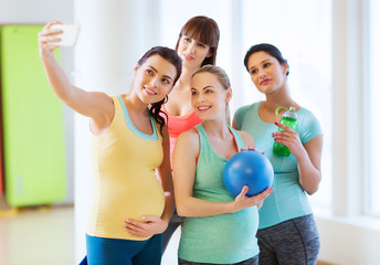 pregnant women taking selfie by smartphone in gym