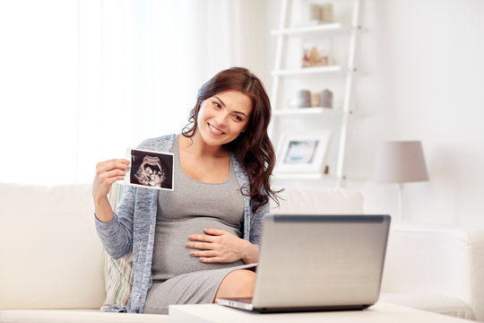 happy pregnant woman with ultrasound image at home