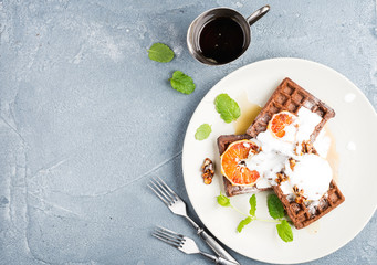 Belgian soft waffles with blood orange, cream, marple syrup and mint  on white plates 