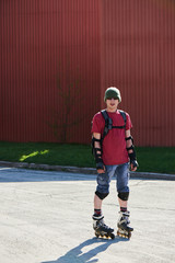 Portrait of a guy in roller skates on a background of red buildings