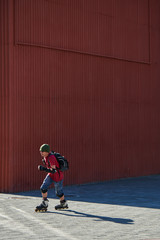 Obraz premium Guy rides on roller skates on the pavement against the red wall
