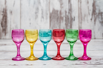 Row of Multi Colored Glasses on White Wooden Background