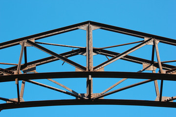 Detail of old rusty metal bridge on blue sky background