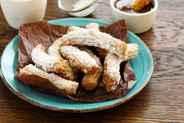 Churros with hot chocolate and powdered sugar.