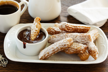 Churros with hot chocolate and powdered sugar.