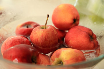 Red apple in glass bowl with water.