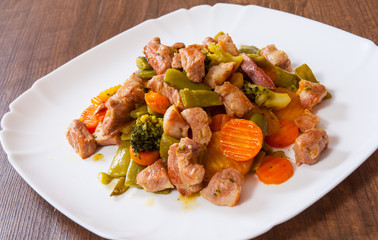 stewed meat with vegetables in a plate on wooden table
