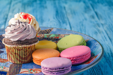 Few tasty cupcakes with macaroons on plate